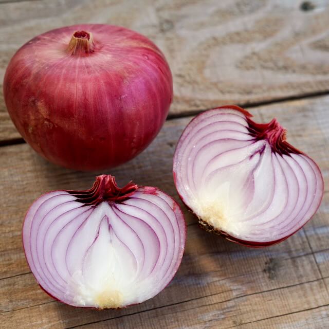 Un oignon Tourne-Sol Oignon Rossa di Milano entier et ses deux moitiés reposent sur une surface en bois. Les motifs superposés violets et blancs des moitiés d&#39;oignon soulignent son allure unique, capturant l&#39;essence de l&#39;oignon rouge.