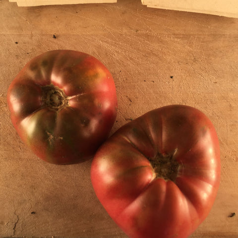 Deux tomates indéterminées Mauve Cherokee Purple du Tourne-Sol sur une table en bois.