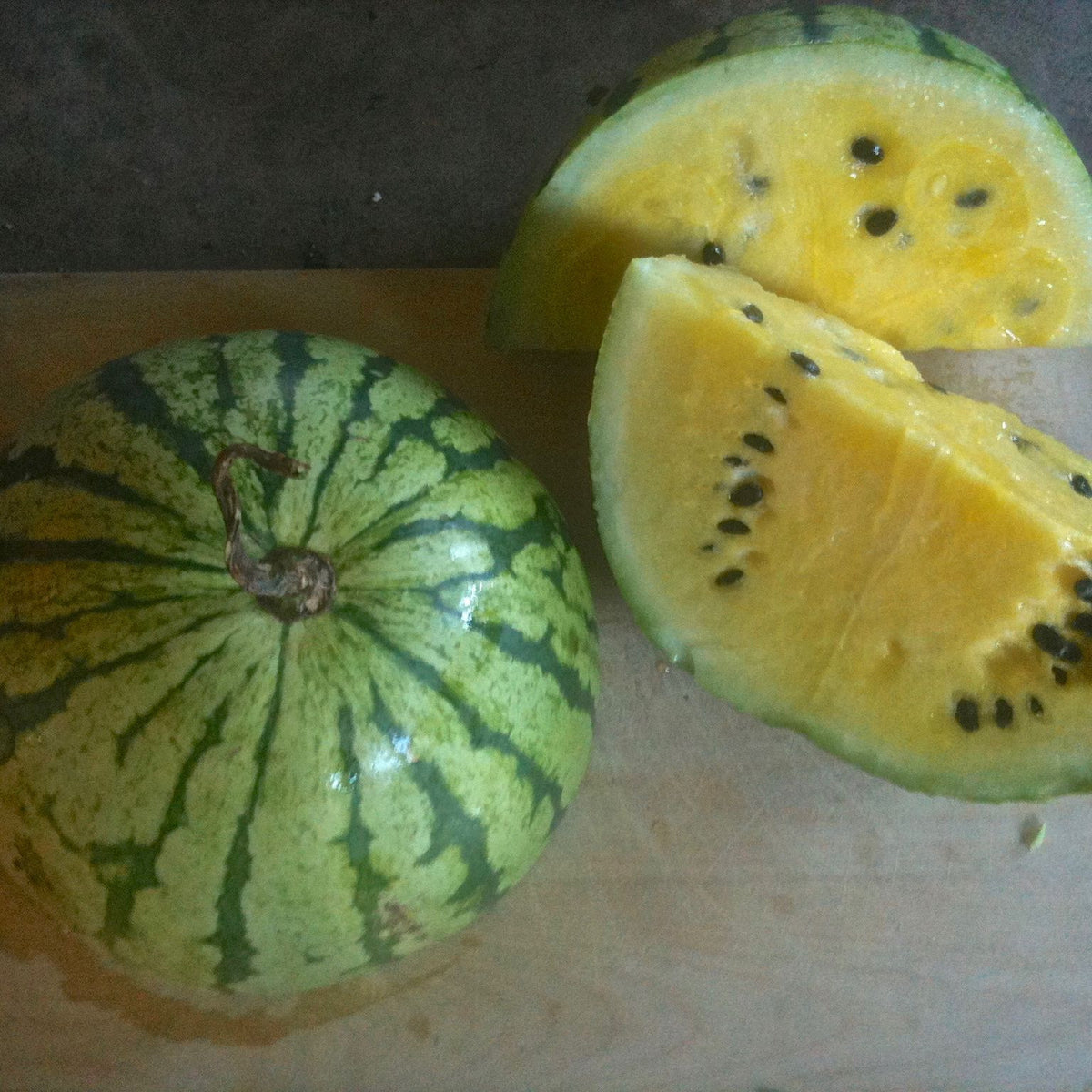 Une tranche de Melon d&#39;Eau Early Moonbeam et une tranche de kiwi sur une planche à découper de Tourne-Sol.